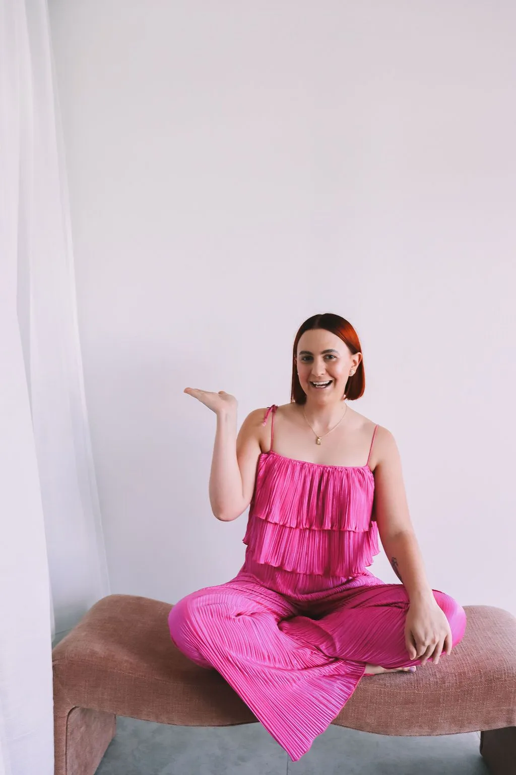 Social Media Strategy for Small Business: The Proven Framework That Turns Followers Into Bookings article image showing Katie in a bright pink set presenting with an open hand