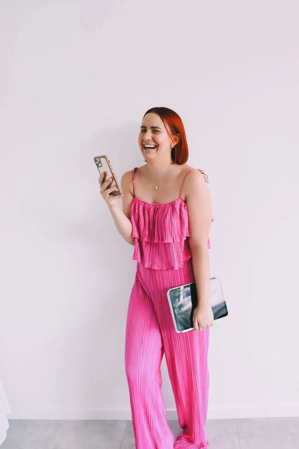 15 Content Ideas for Small Business Owners Who Are Sick of Staring at a Blank Page article image showing Katie in a bright pink set holding her smartphone